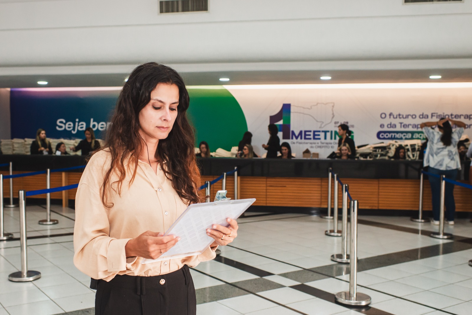Coordenadora com lista de credenciamento na entrada do congresso