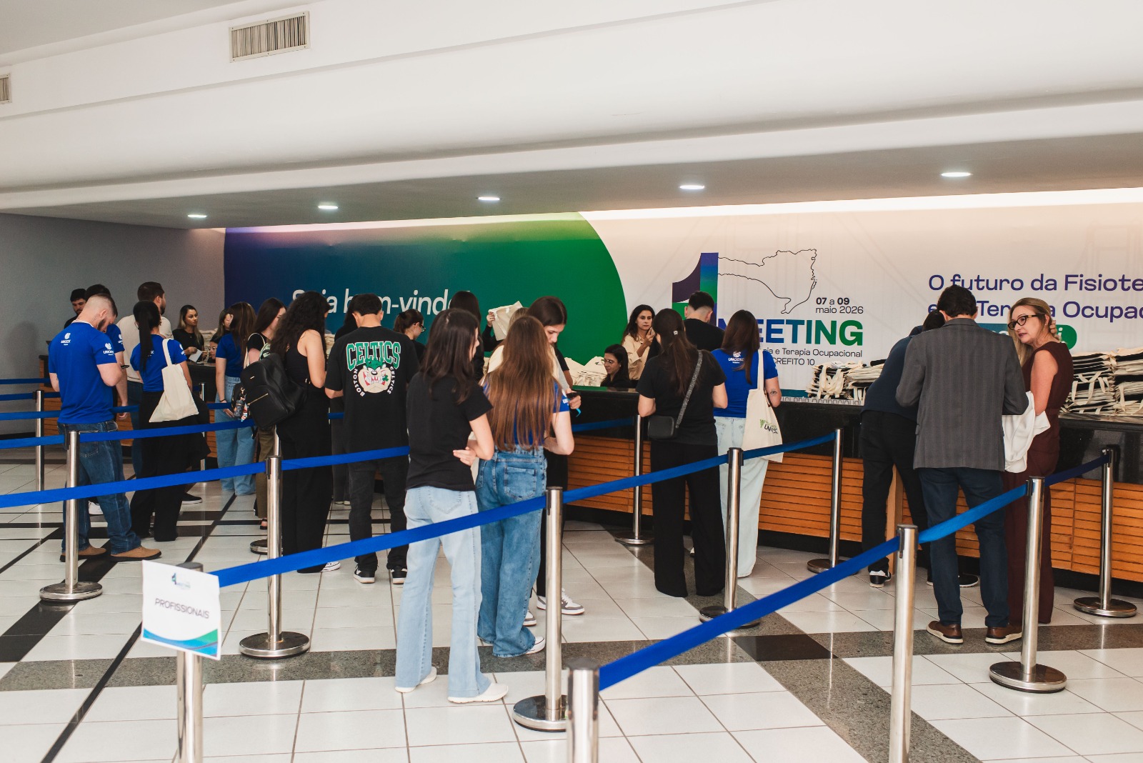 Participantes em fila organizada no balcão de credenciamento